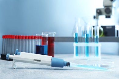 Photo of Laboratory analysis. Micropipette, petri dish, beakers and test tubes on light grey table