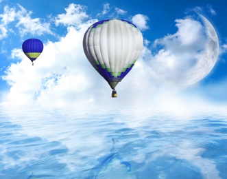 Image of Fantastic dreams. Hot air balloons in blue sky with clouds and crescent moon over sea