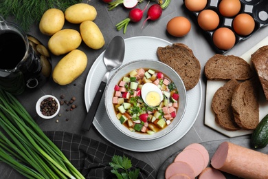 Flat lay composition of cold okroshka with kvass and other ingredients on grey table. Traditional Russian summer soup