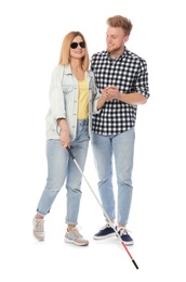 Photo of Young man helping blind person with long cane on white background