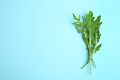 Photo of Fresh arugula on light blue background, flat lay. Space for text