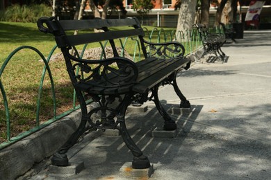 Photo of Beautiful old black bench near pathway in park