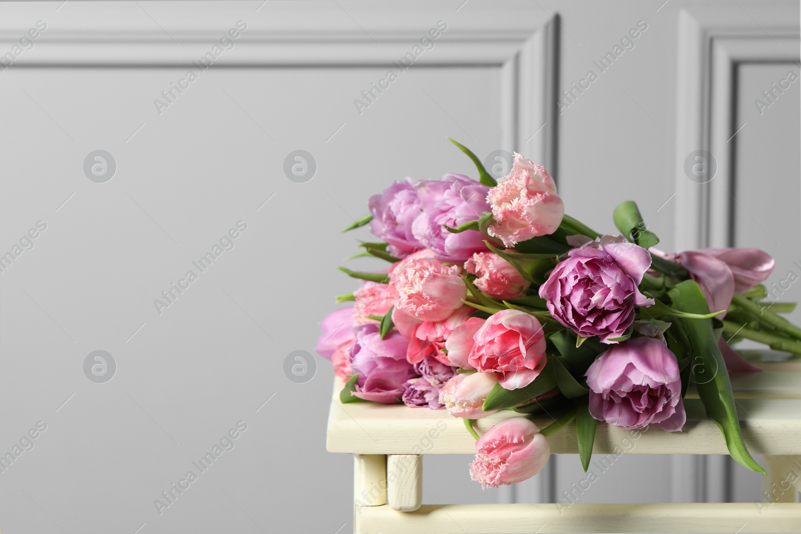 Photo of Beautiful bouquet of colorful tulip flowers on stool