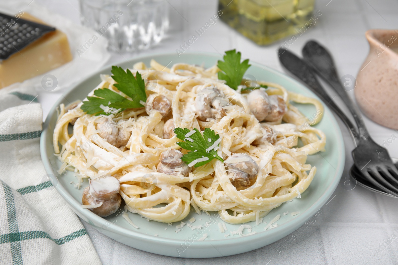 Photo of Delicious pasta with mushrooms on white tiled table, closeup