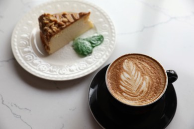 Cup of fresh coffee and dessert on white marble table, above view