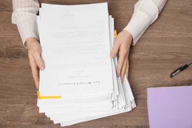 Woman working with documents at wooden table, top view