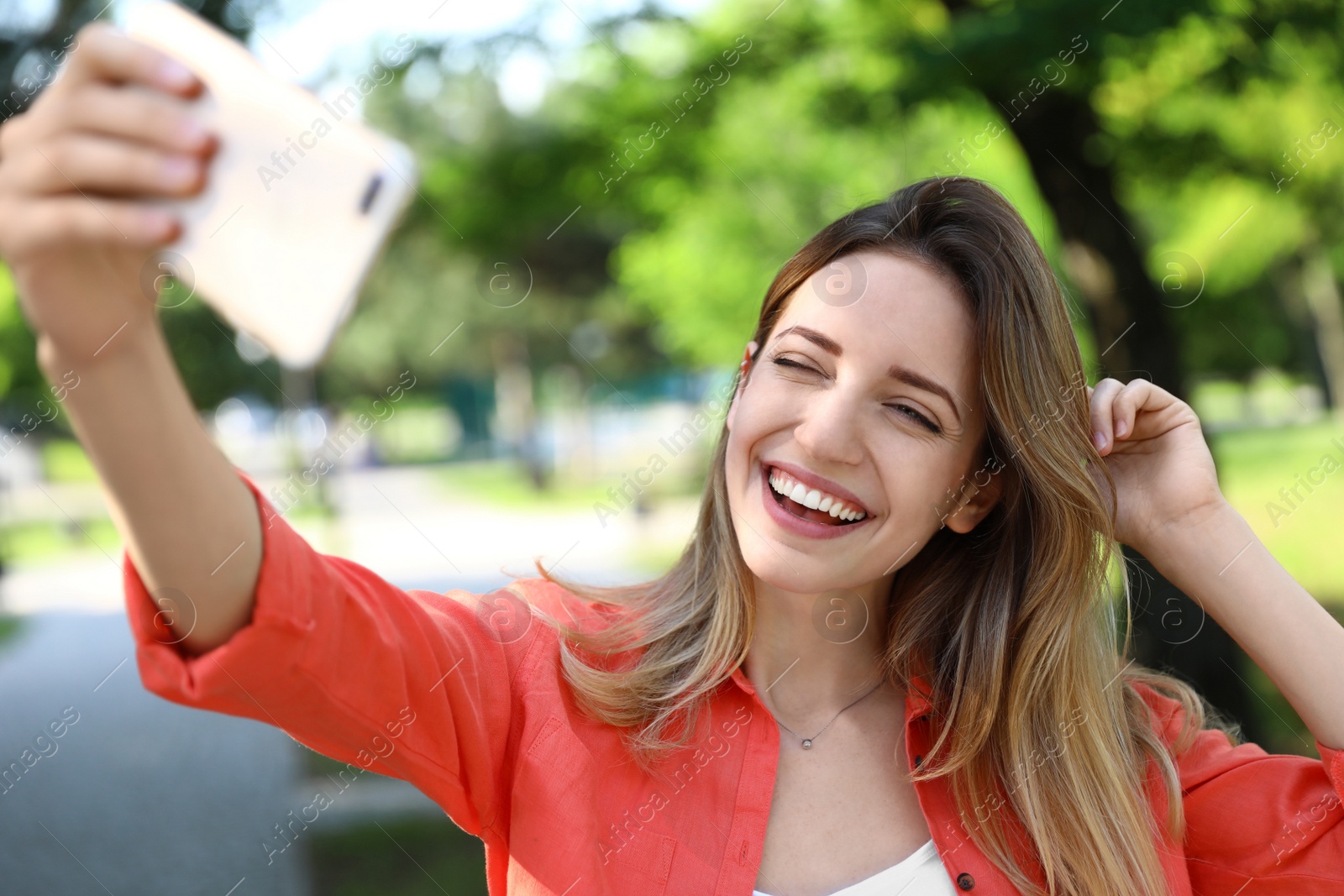 Photo of Happy young woman taking selfie in park