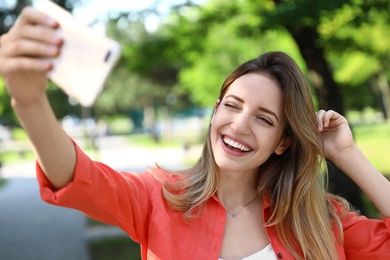 Photo of Happy young woman taking selfie in park