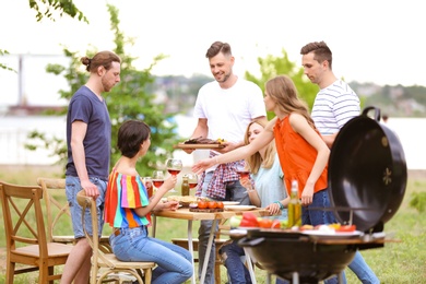 Young people having barbecue with modern grill outdoors