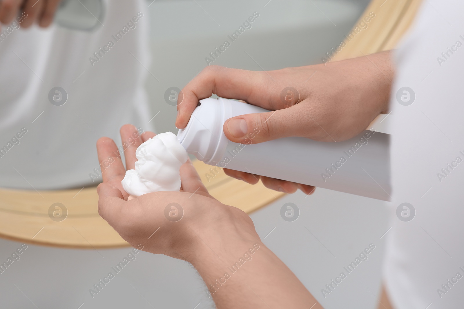 Photo of Man applying shaving foam onto hand in bathroom, closeup