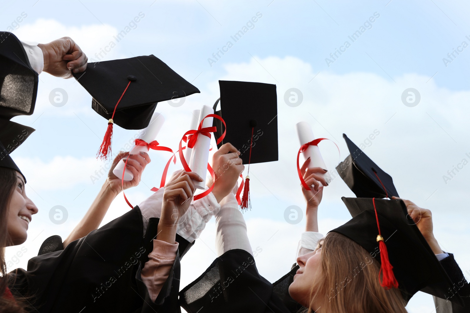 Photo of Group of students with diplomas outdoors. Graduation ceremony