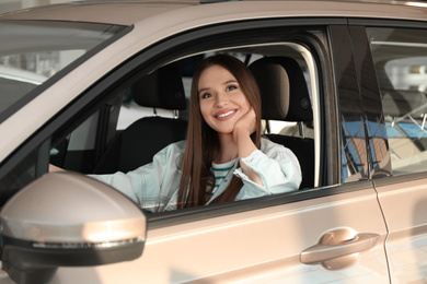 Photo of Beautiful woman sitting in modern car at dealership