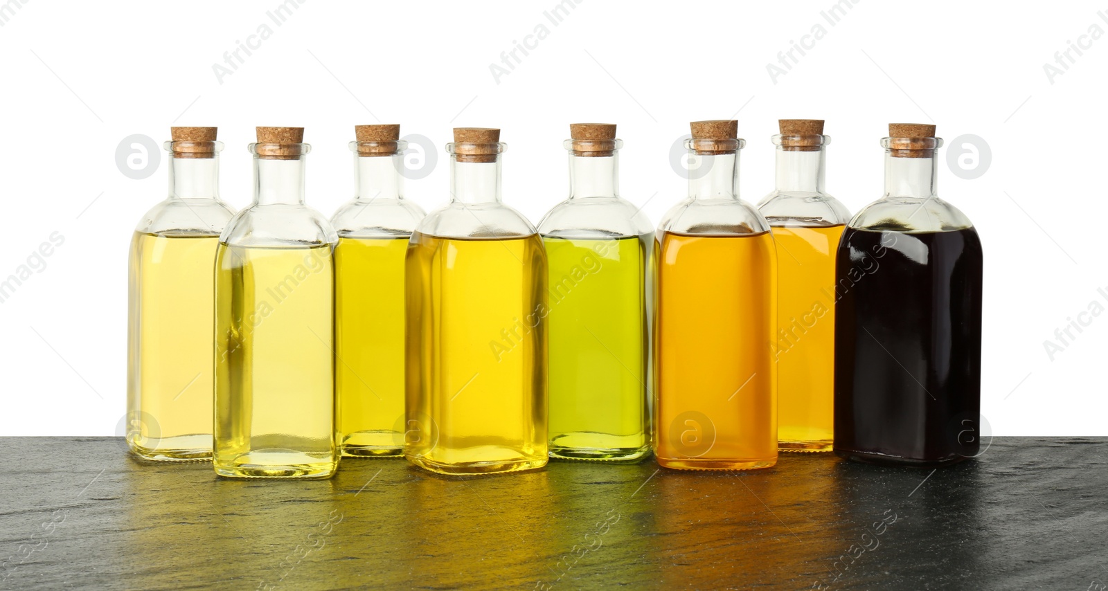 Photo of Vegetable fats. Bottles of different cooking oils on wooden table against white background