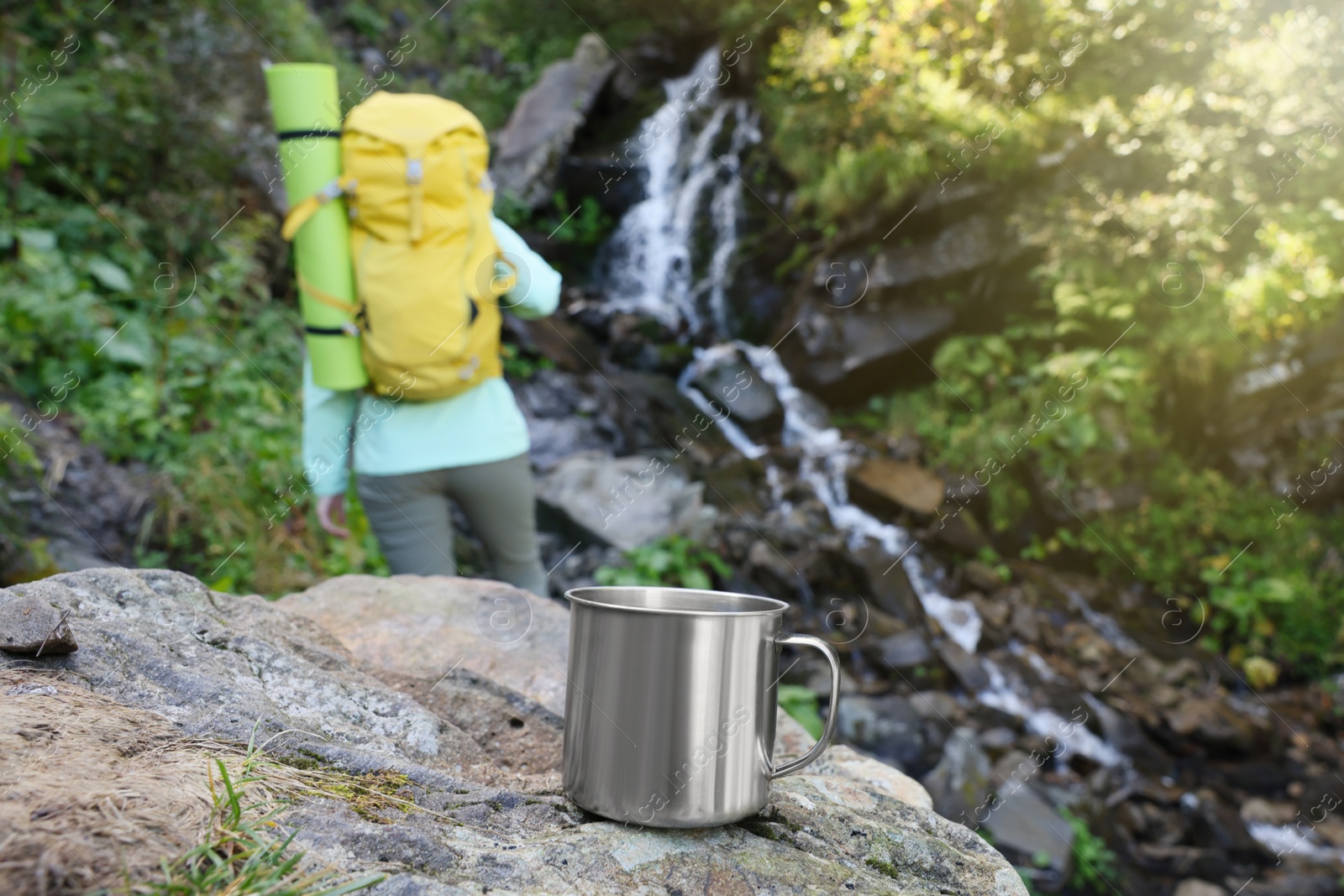 Photo of Tourist near waterfall in mountains, focus on cup