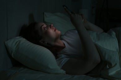 Woman using smartphone on bed at night. Internet addiction