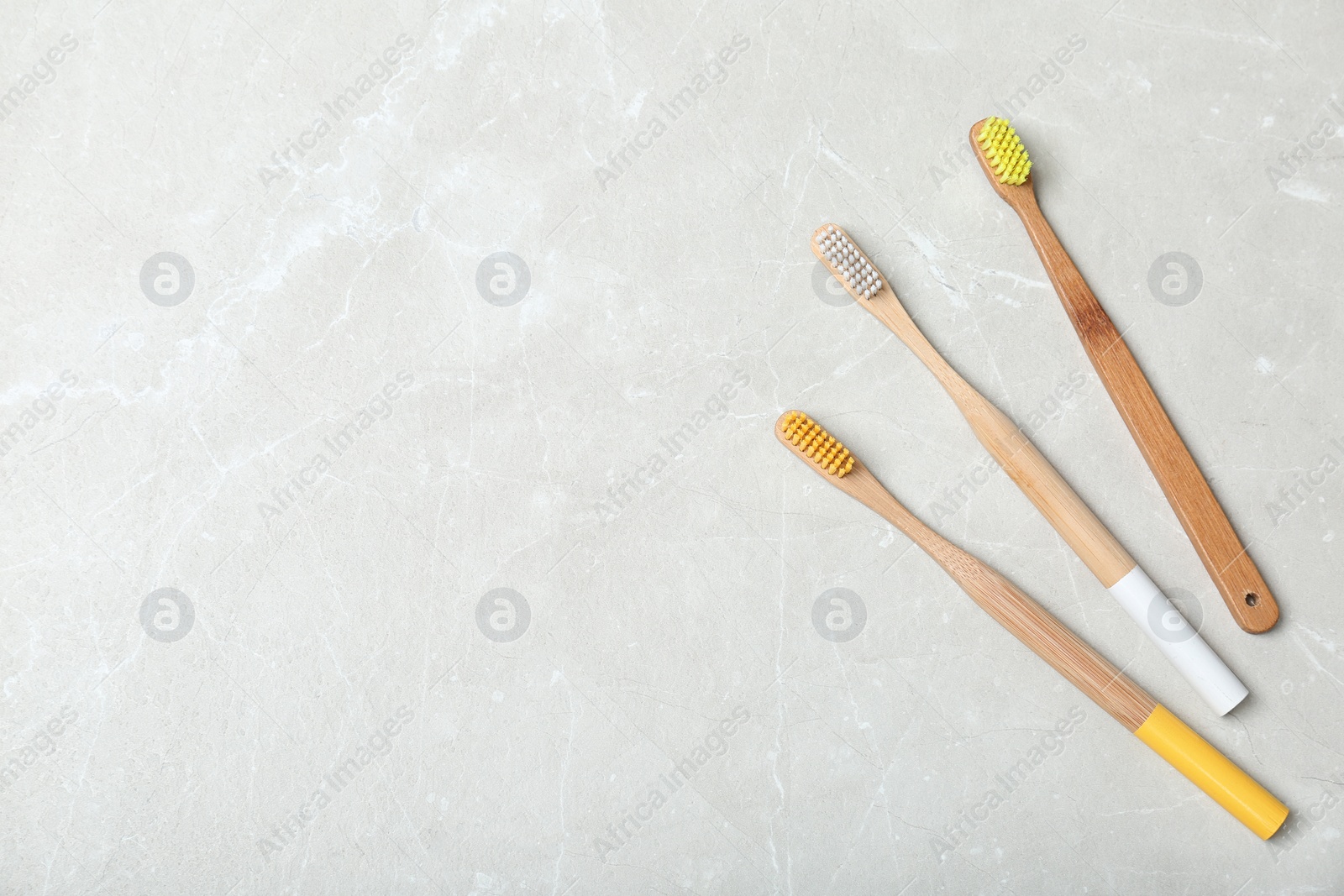 Photo of Bamboo toothbrushes and space for text on light background, top view. Dental care