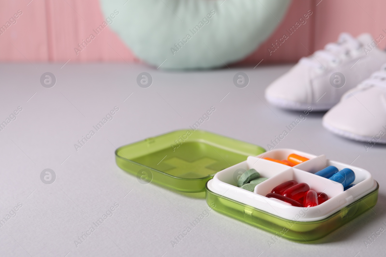 Photo of Different pills in container on grey table, closeup. Space for text