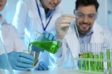 Group of scientists working with sample in chemistry laboratory, closeup