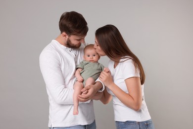 Photo of Happy family. Parents with their cute baby on grey background