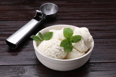 Delicious vanilla ice cream, mint and scoop on wooden table