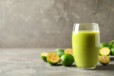 Photo of Fresh feijoa smoothie and fresh fruits on grey table, closeup. Space for text