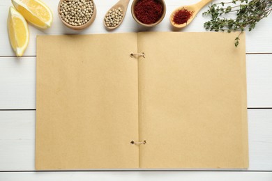 Photo of Blank recipe book and different ingredients on white wooden table, flat lay. Space for text