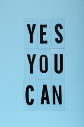 Photo of Phrase Yes You Can of plastic letters on light blue background, top view. Motivational quote