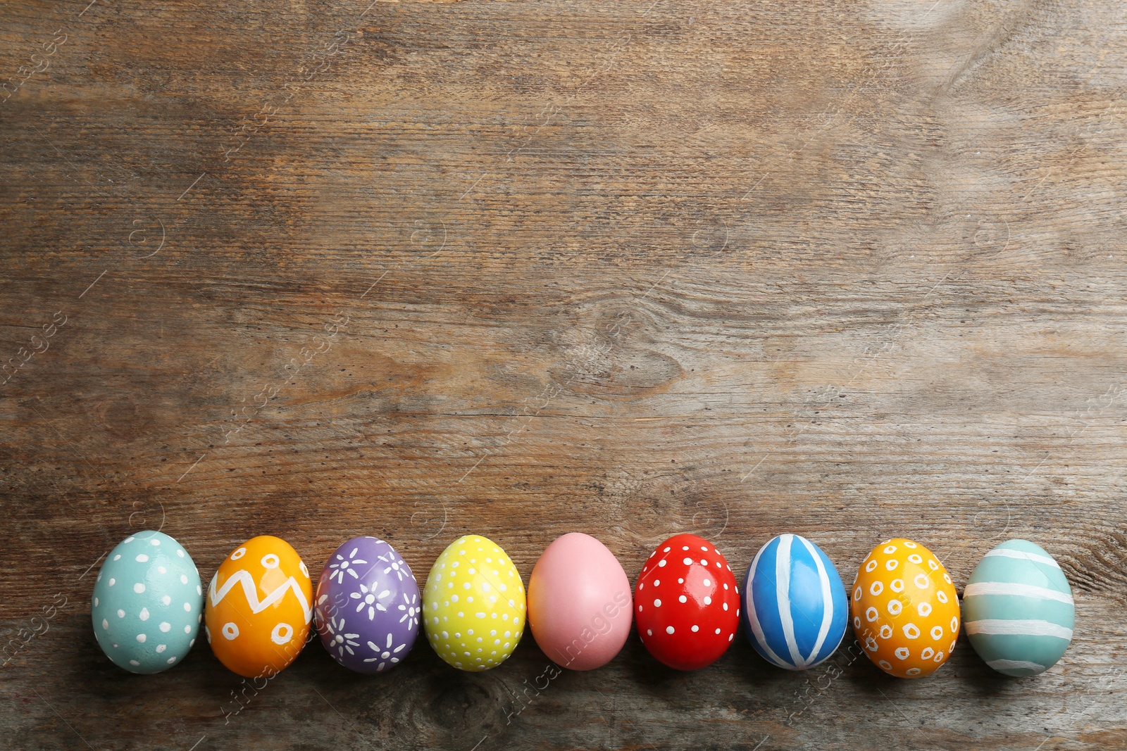 Photo of Flat lay composition of painted Easter eggs on wooden table, space for text