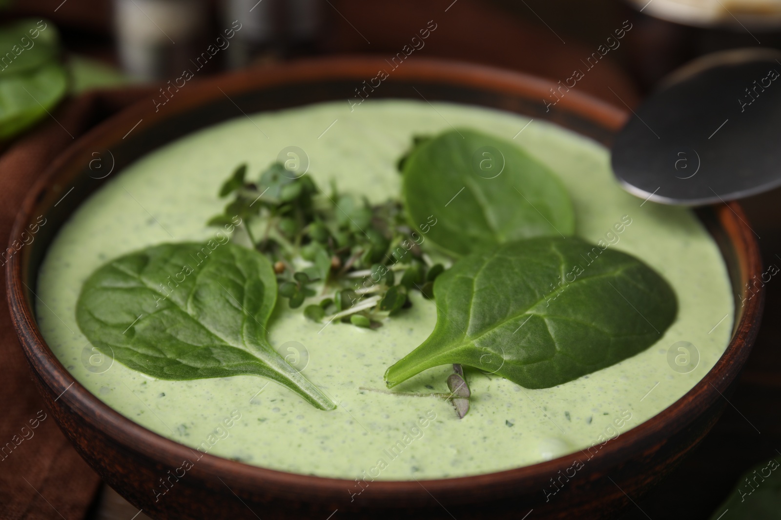 Photo of Delicious spinach cream soup served on wooden table, closeup