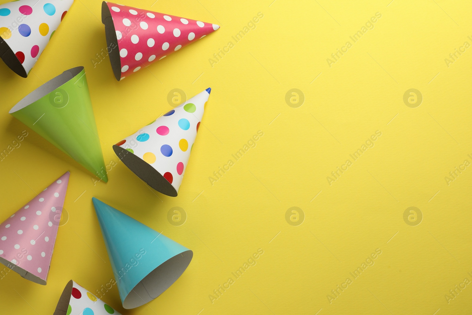 Photo of Beautiful party hats on yellow background, top view. Space for text