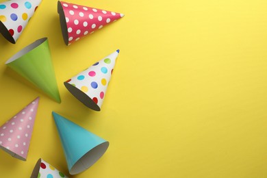 Photo of Beautiful party hats on yellow background, top view. Space for text
