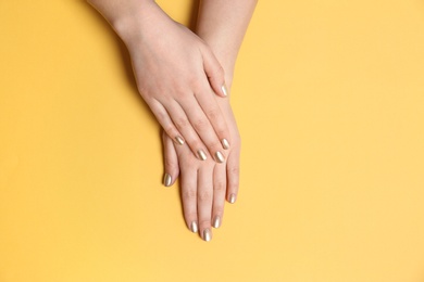 Photo of Woman showing golden manicure on color background, top view with space for text. Nail polish trends
