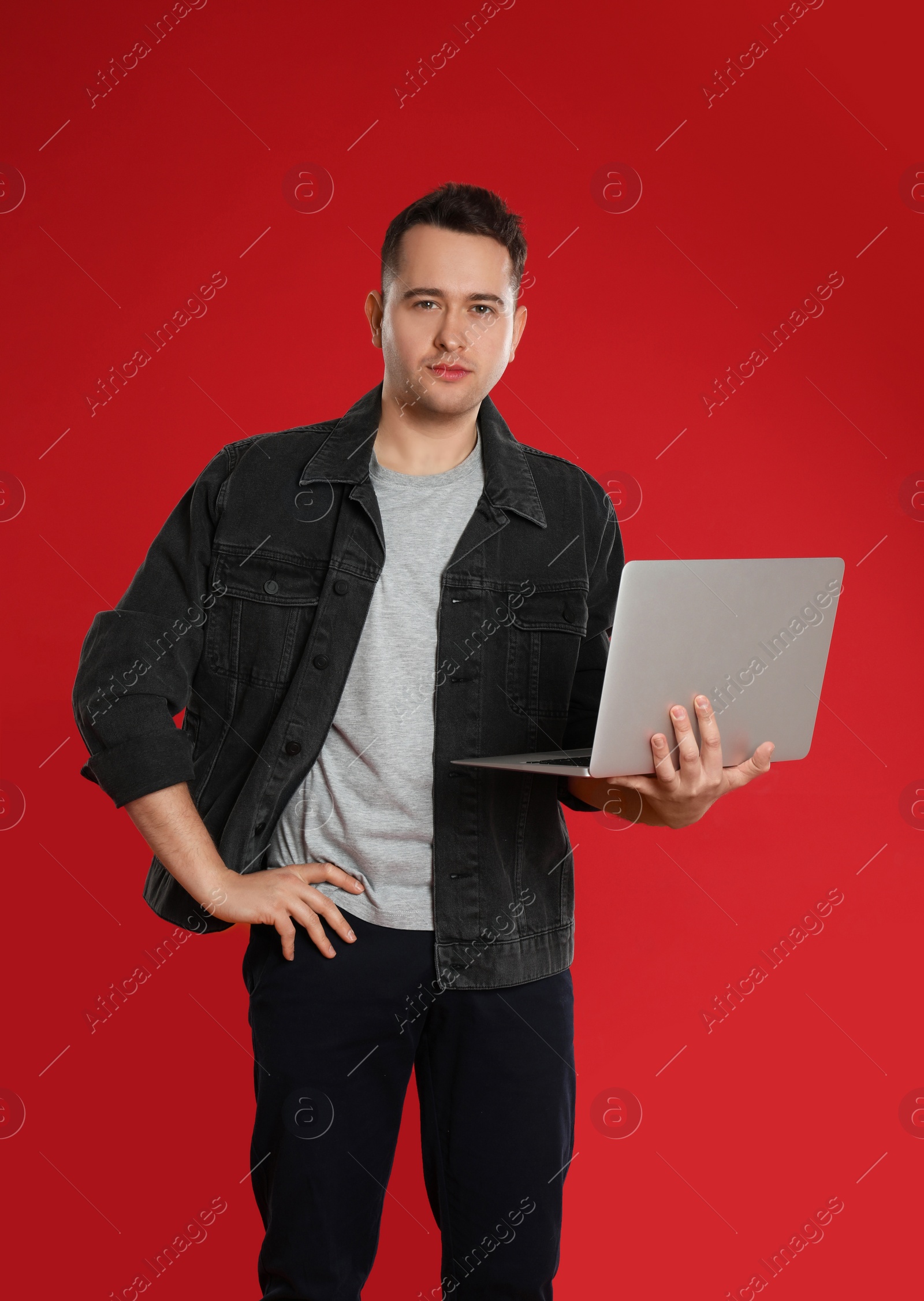 Photo of Young man holding laptop on red background