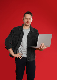 Photo of Young man holding laptop on red background