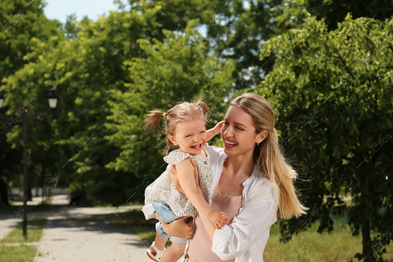 Photo of Happy mother with her daughter having fun in park. Space for text