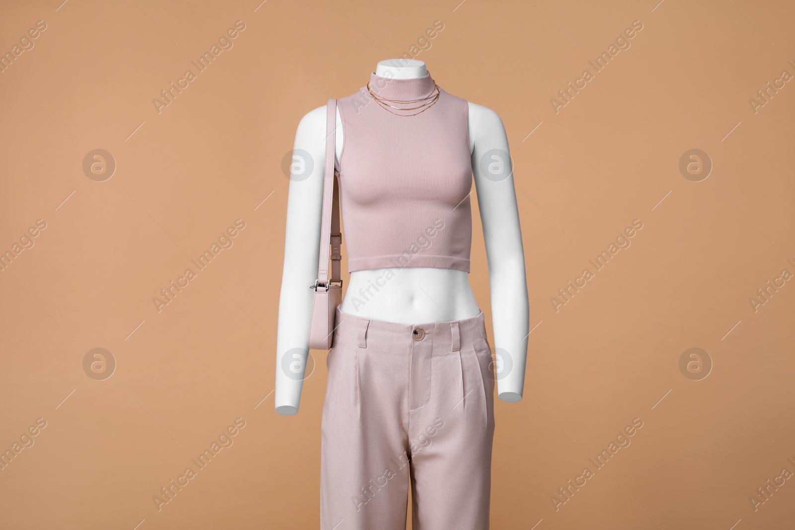 Photo of Female mannequin with bag dressed in stylish crop top and pants on beige background