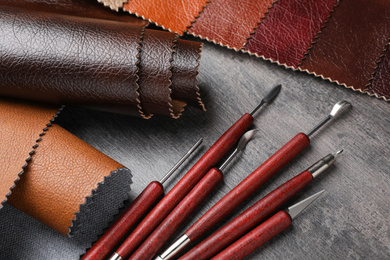 Photo of Leather samples and craftsman tools on grey stone background, above view