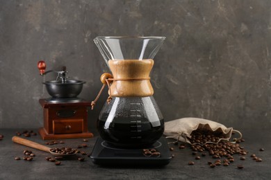 Photo of Making drip coffee. Glass chemex coffeemaker, beans and scales on gray table
