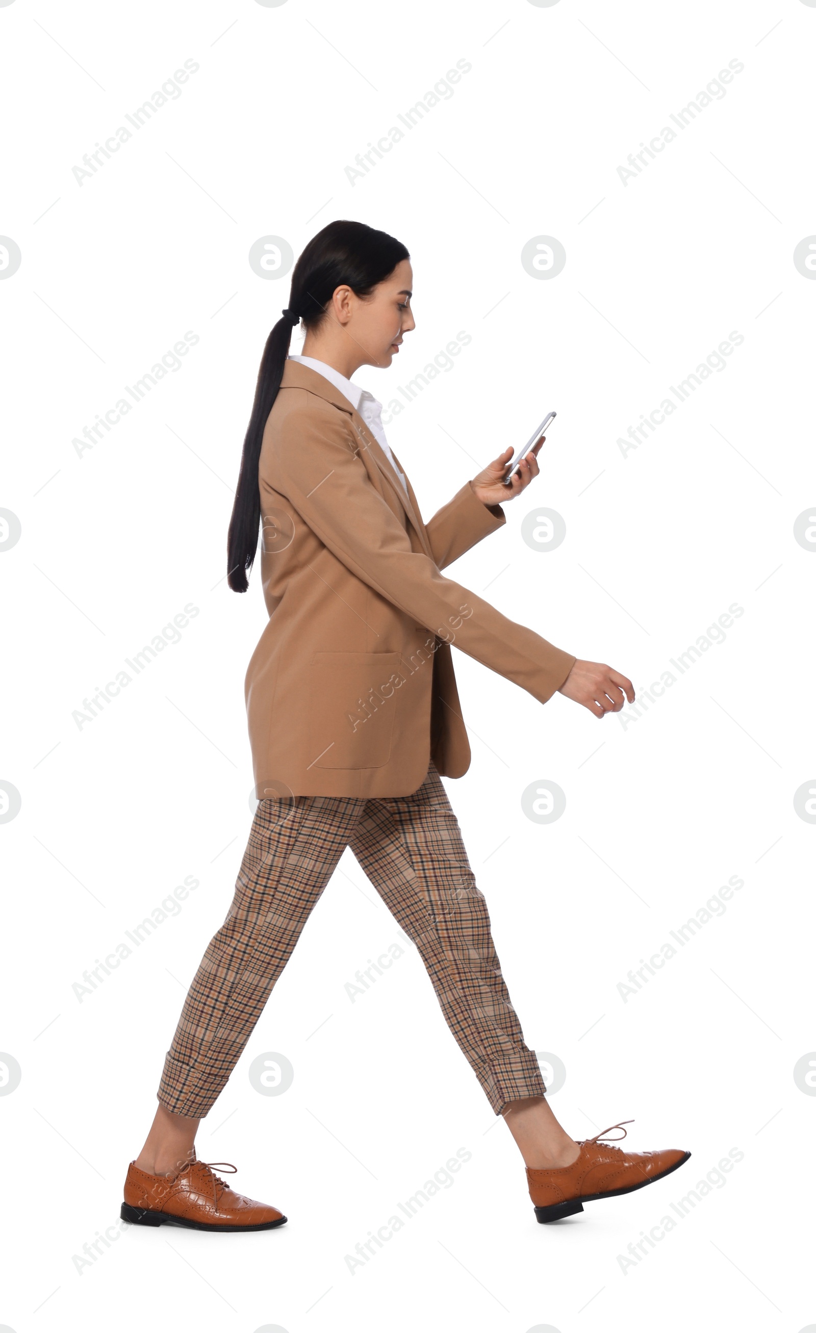 Photo of Young businesswoman using smartphone while walking on white background