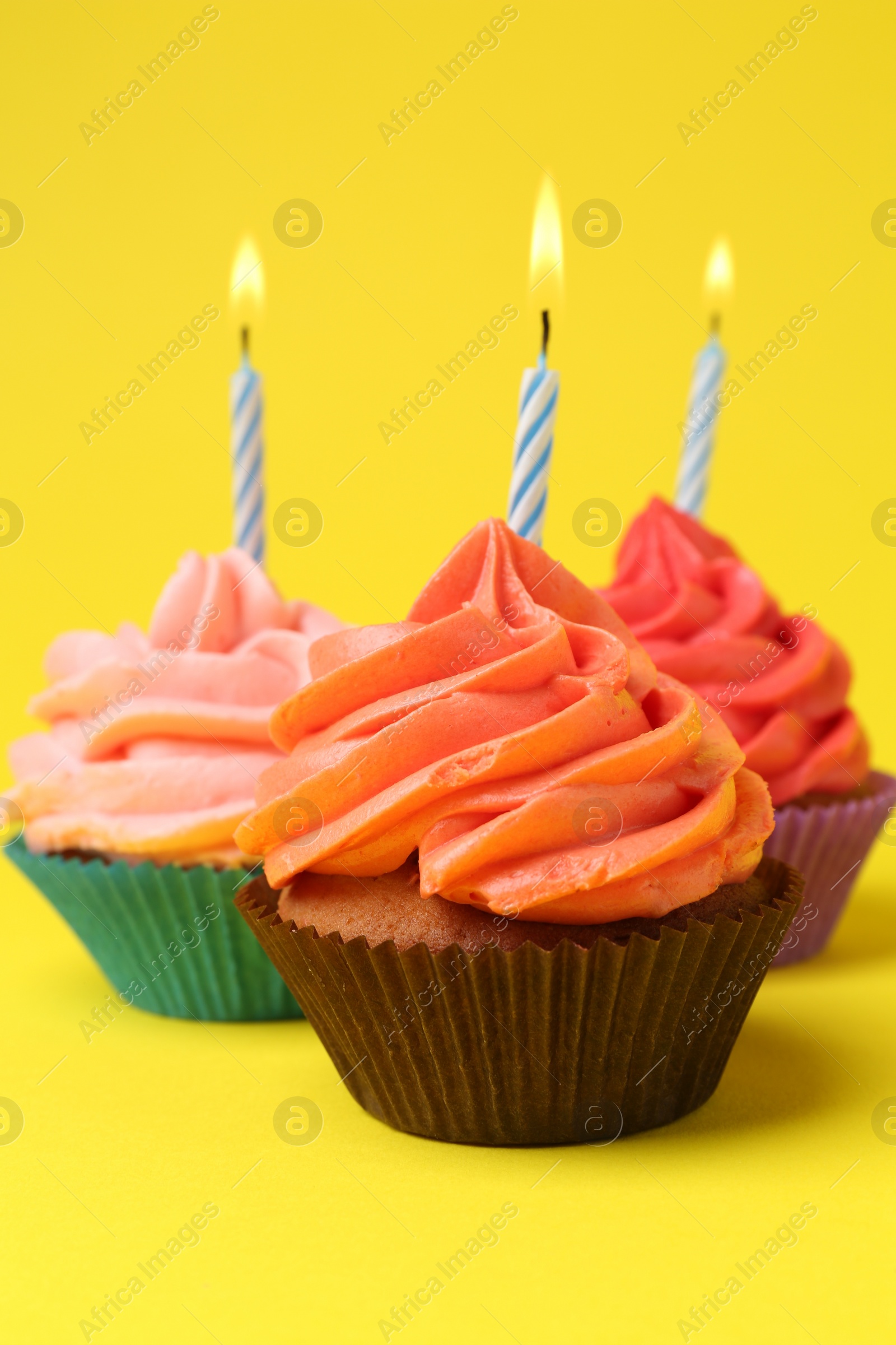 Photo of Delicious birthday cupcakes with bright cream on yellow background