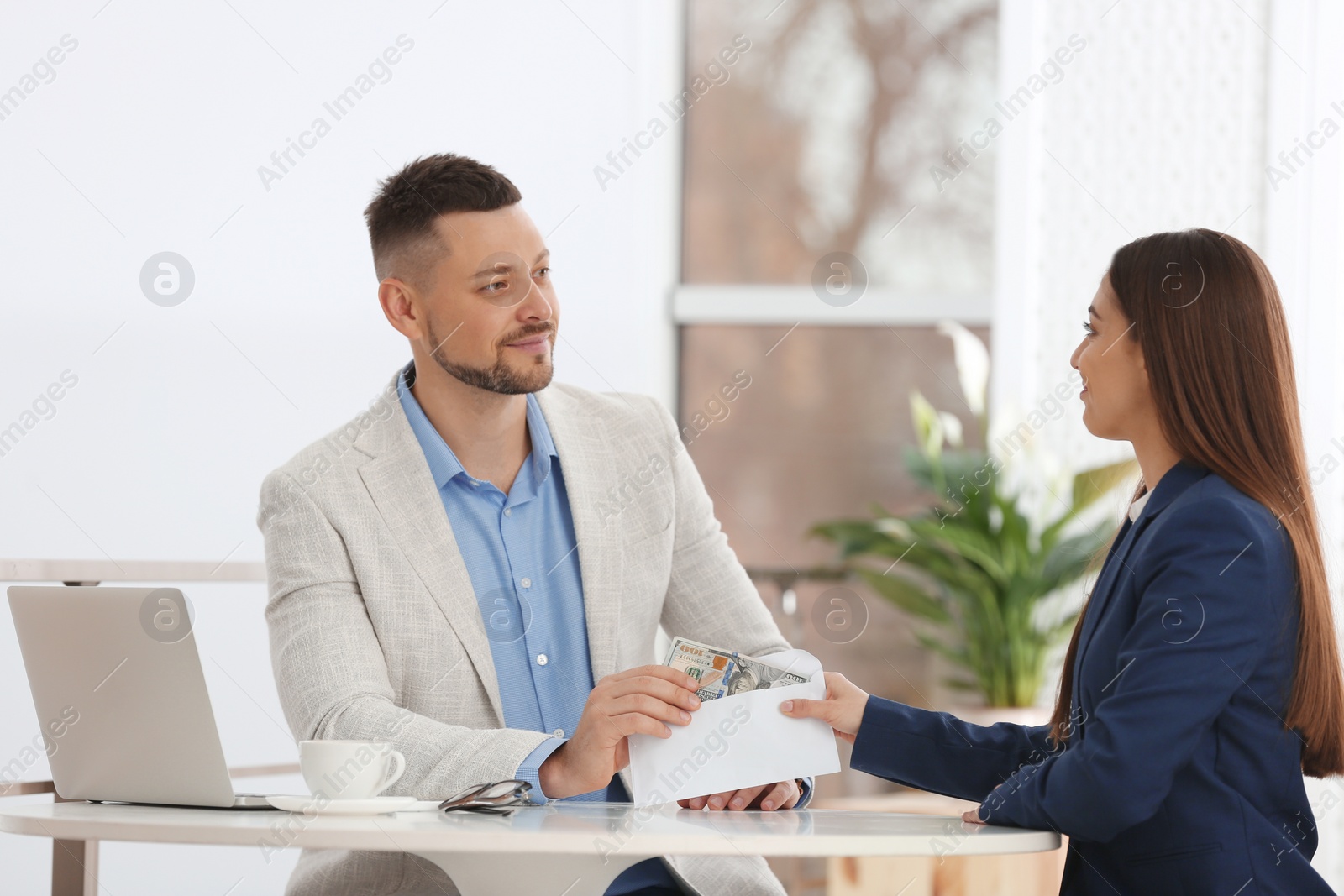 Photo of Woman giving bribe to man at table indoors