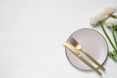 Photo of Stylish table setting with cutlery and flowers on white wooden background, flat lay. Space for text