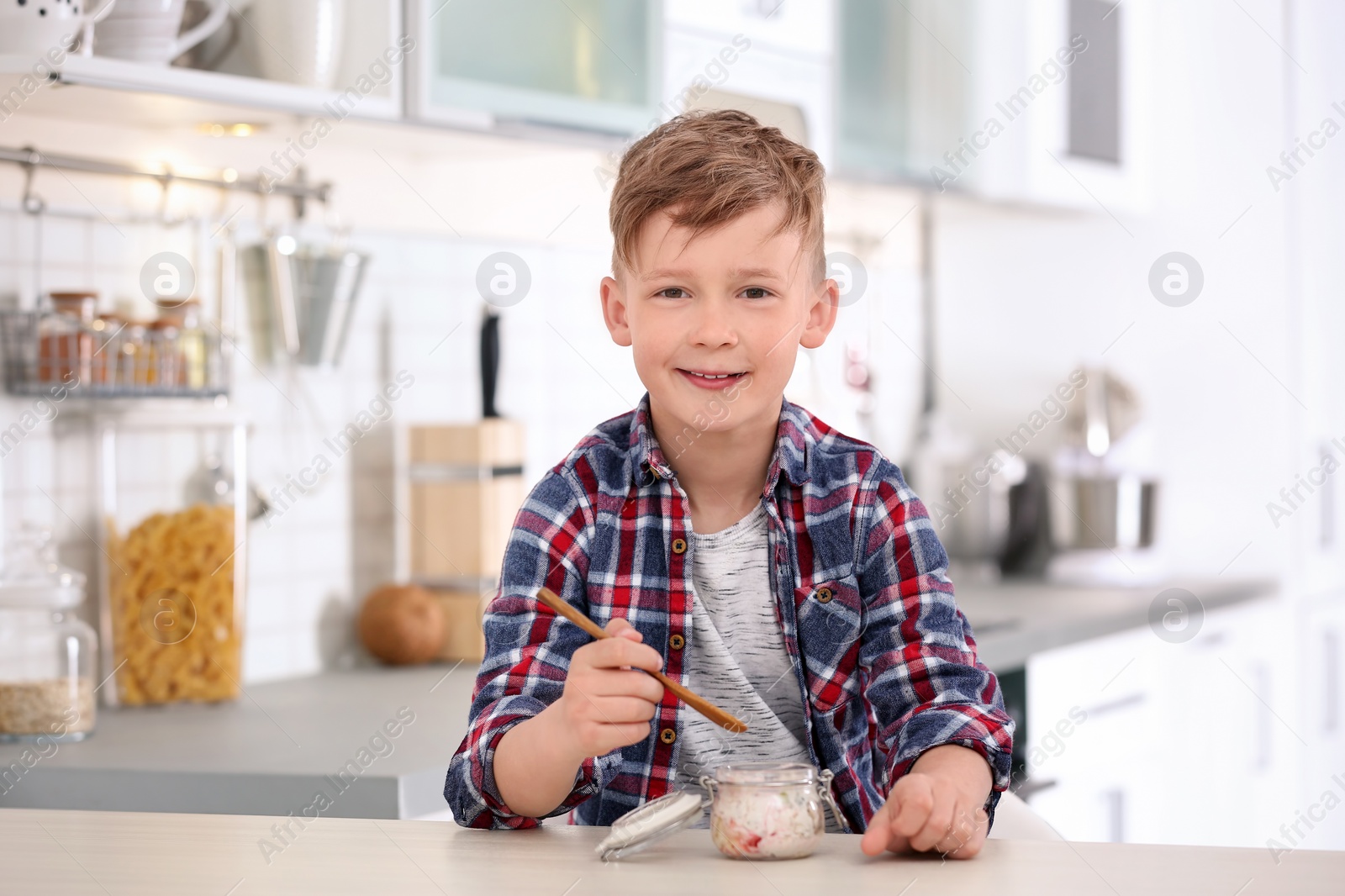 Photo of Little boy with yogurt in kitchen