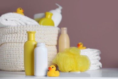 Photo of Bottles of baby cosmetic products and rubber duck on white table. Space for text