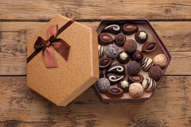 Photo of Open box of delicious chocolate candies on wooden table, top view