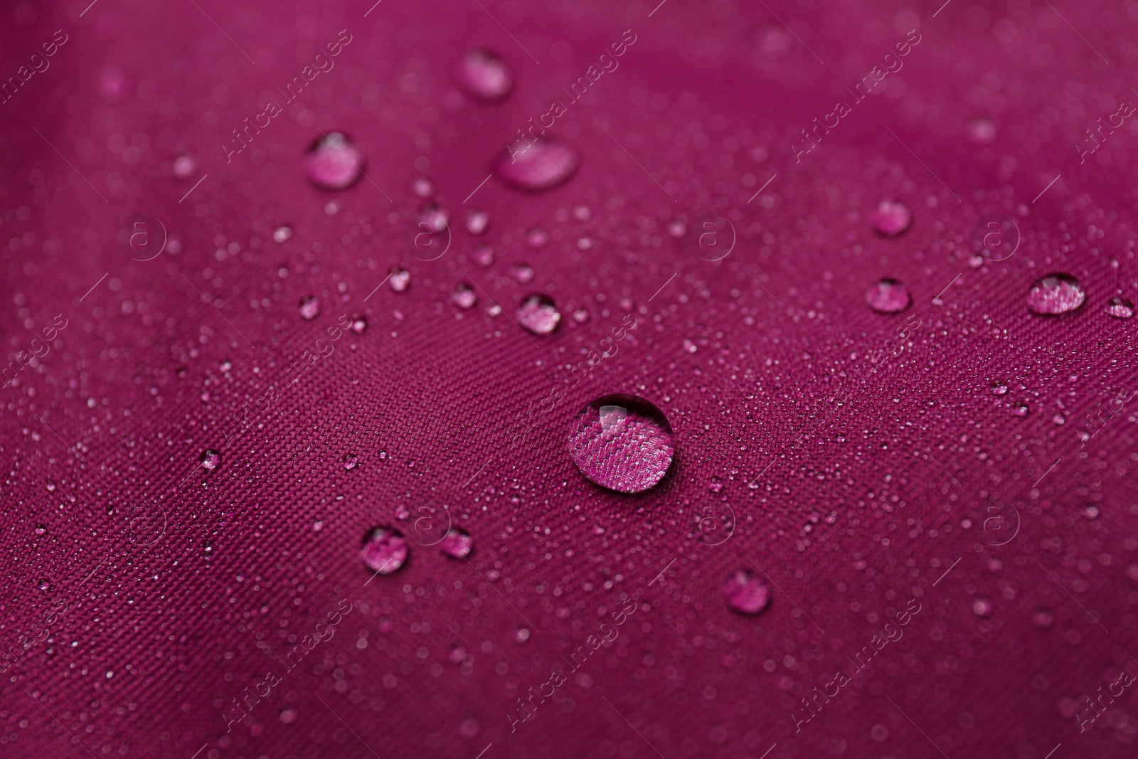 Photo of Dark pink waterproof fabric with water drops as background, closeup