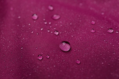 Photo of Dark pink waterproof fabric with water drops as background, closeup