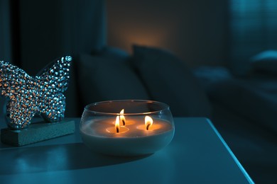 Photo of Burning scented candle on bedside table in bedroom at night