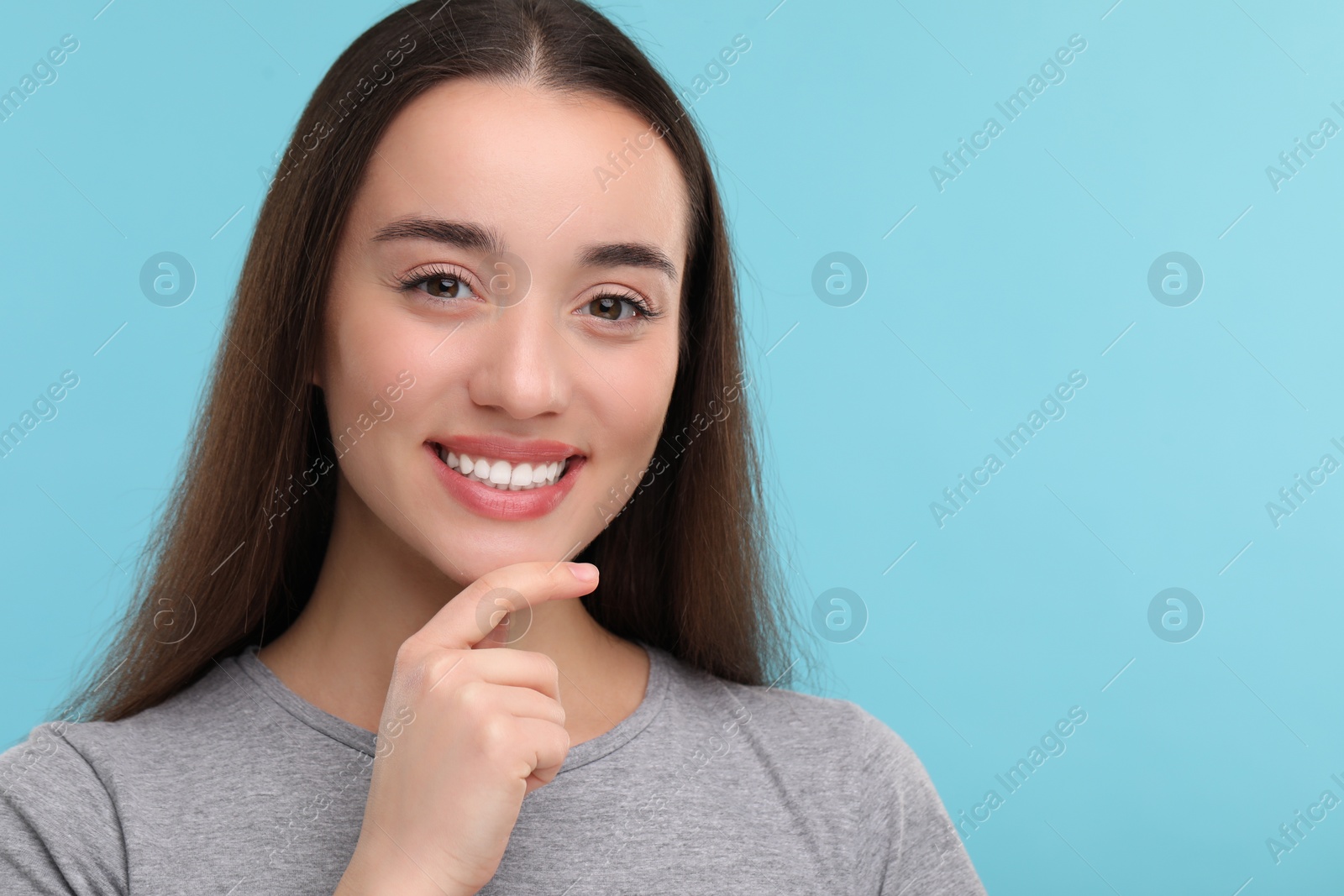 Photo of Young woman with clean teeth smiling on light blue background, space for text