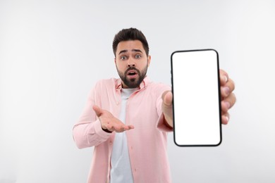 Surprised man showing smartphone in hand on white background